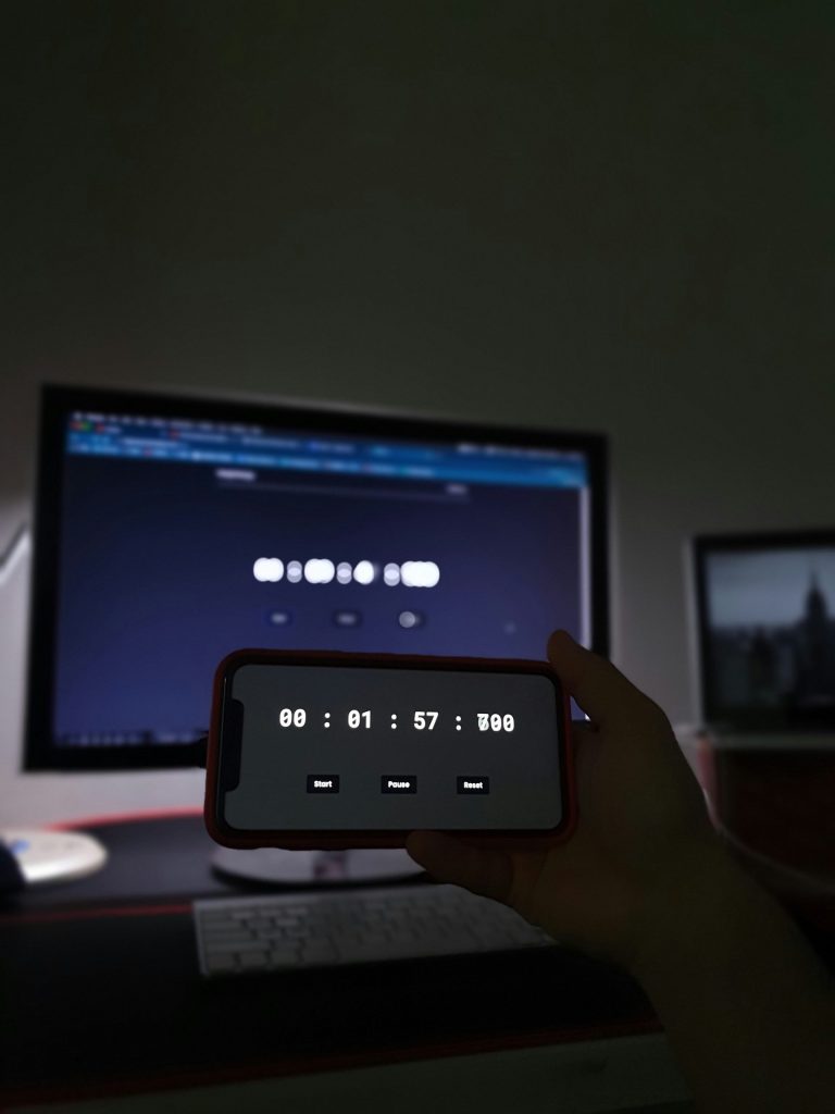 Eine Person, die ein Handy vor einem Computer hält